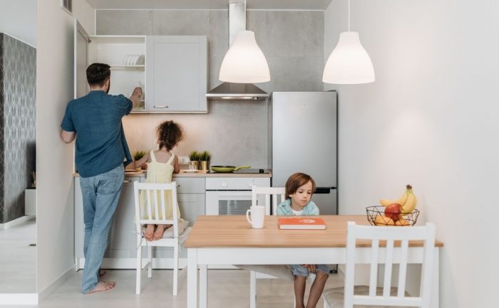 A father and children enjoying quality time in a bright, modern kitchen area.
